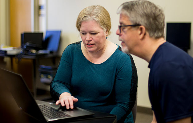 A Student and Advisor Review Materials on a Computer.