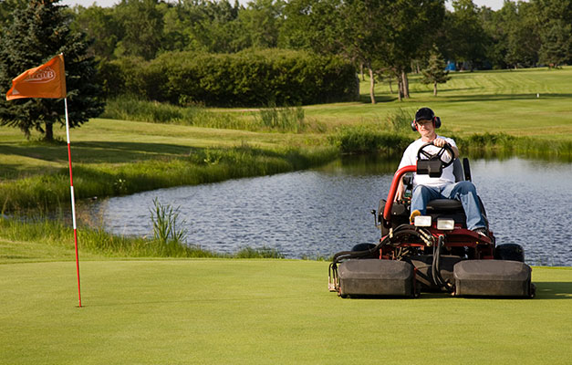 golf course green and man on lawn mower